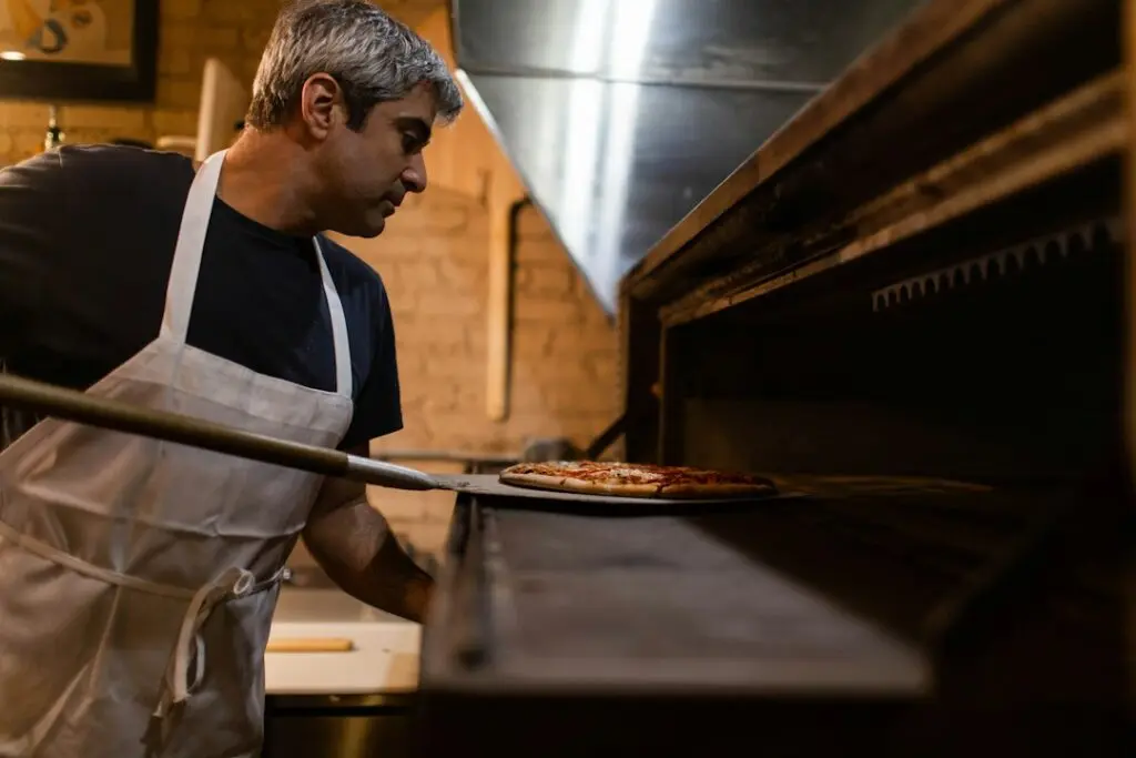 Pizzaiolo inforna una pizza nel forno a legna